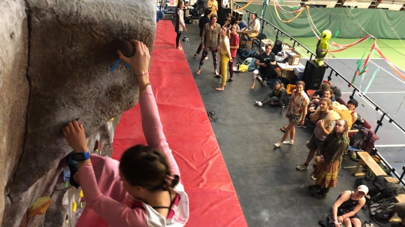 Climber climbs at the climbing comp with students looking on