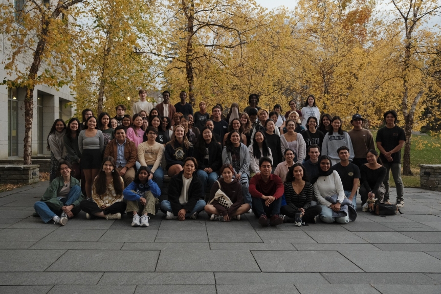 A large group of students face the camera and smile.