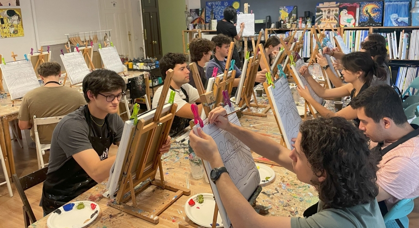 Students sitting at a table and painting