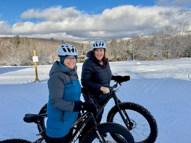 Photo of two employees on bikes in the snow