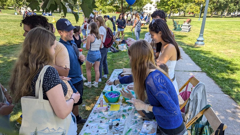 Peer educators and students at a table outside during an event.
