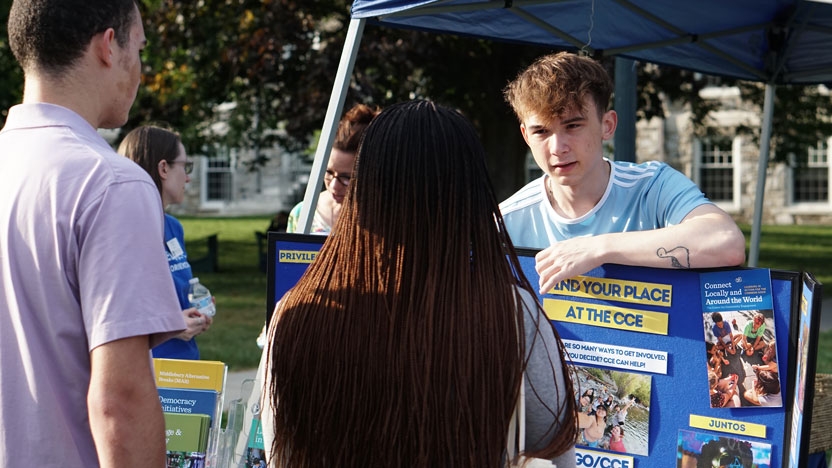 A student talking with other students outside in the fall at the Student Involvement Fair.