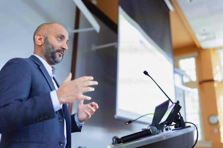 a male bearded professor stands at a podium 