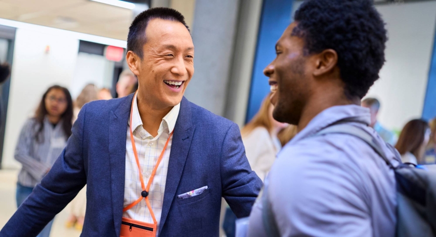 An alumnus laughs with a student.