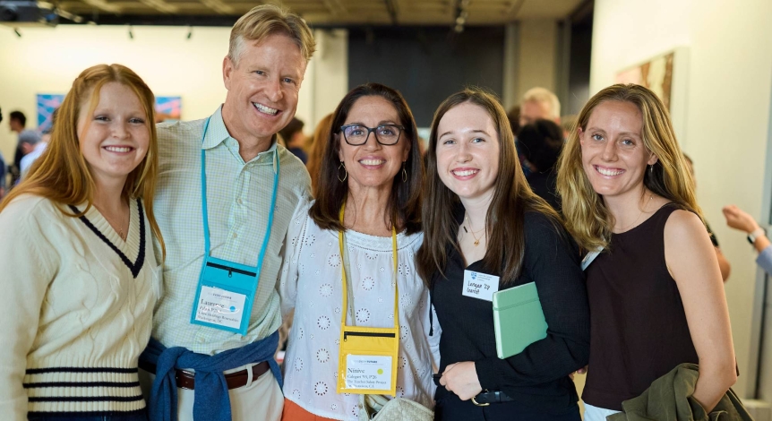 5 people stand together and smile into the camera.