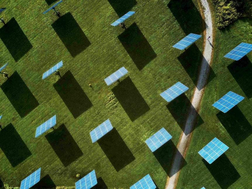 aerial view of solar field with solar panels and dirt path running through on right