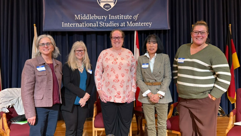 People stand for a photo in front of a banner for the Middlebury Institute.