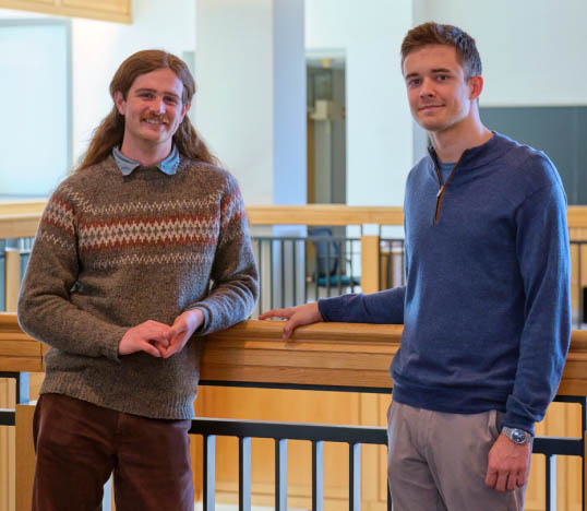 Two students sanding by a railing