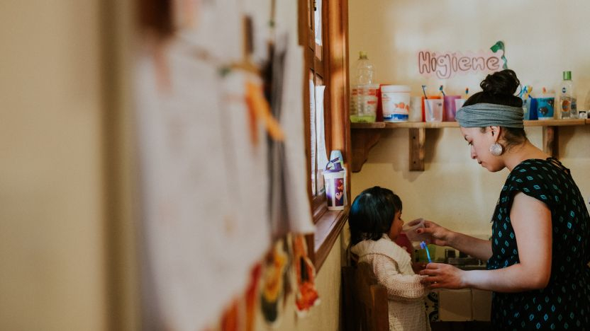 Adult giving child water in a daycare center