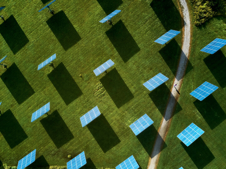 aerial photo of solar panels with green grass and path