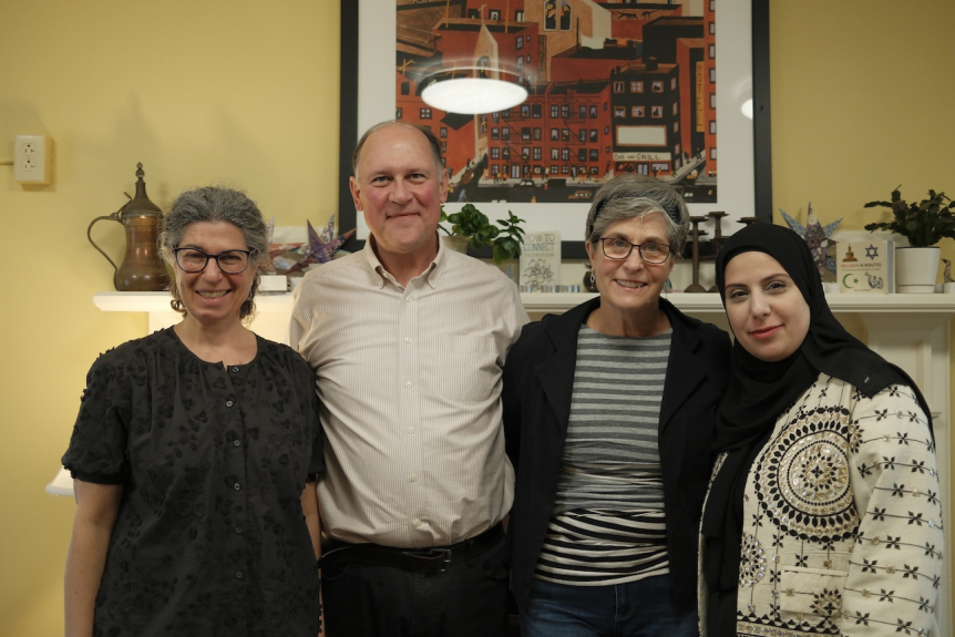 four smiling staff member standing in front of mantel