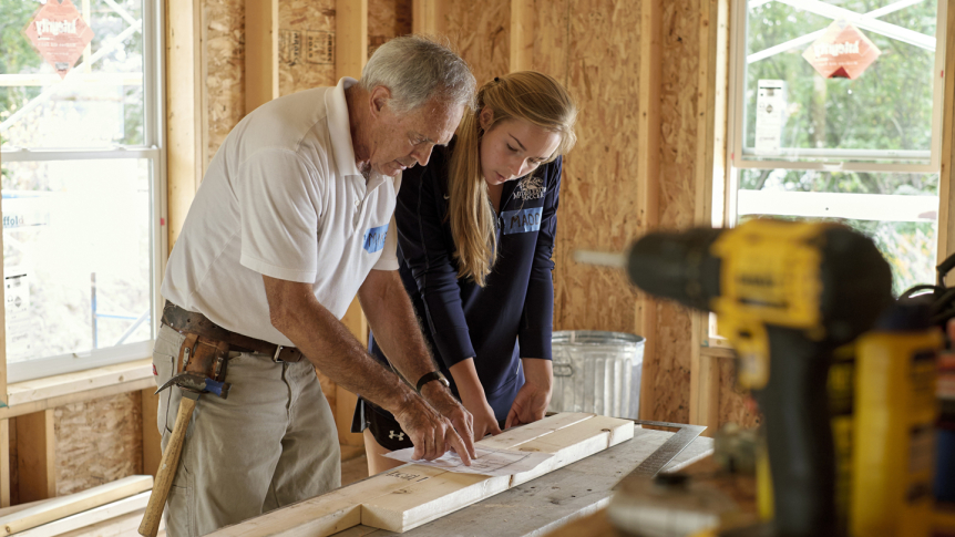 A student works with a builder for a local Habitat for Humanity project