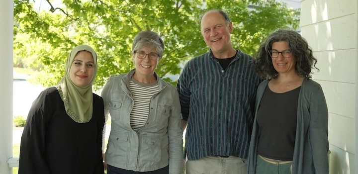 four smiling people with trees in the background