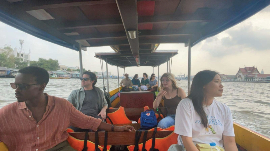 Several students ride on a small boat in Southeast Asia