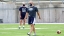 A Middlebury football player and coach participate in practice wearing masks.