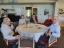 Five colleagues sitting at a round table smiling with one taking a drink.
