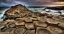 hexagonal rock formations with surf and dark skies