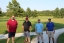 Colleagues standing together playing golf