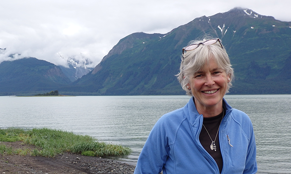 Heather Vuillet Lende in light blue fleece sweater, with lake and mountains in the background