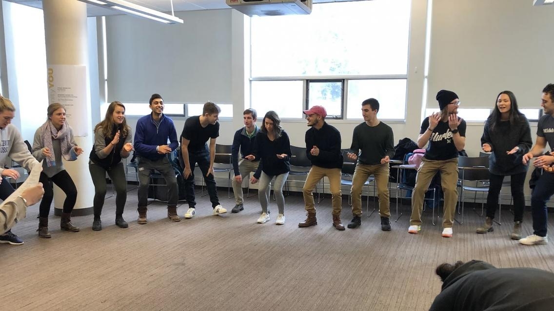 A circle of college students take part in a physicality-based public speaking exercise.