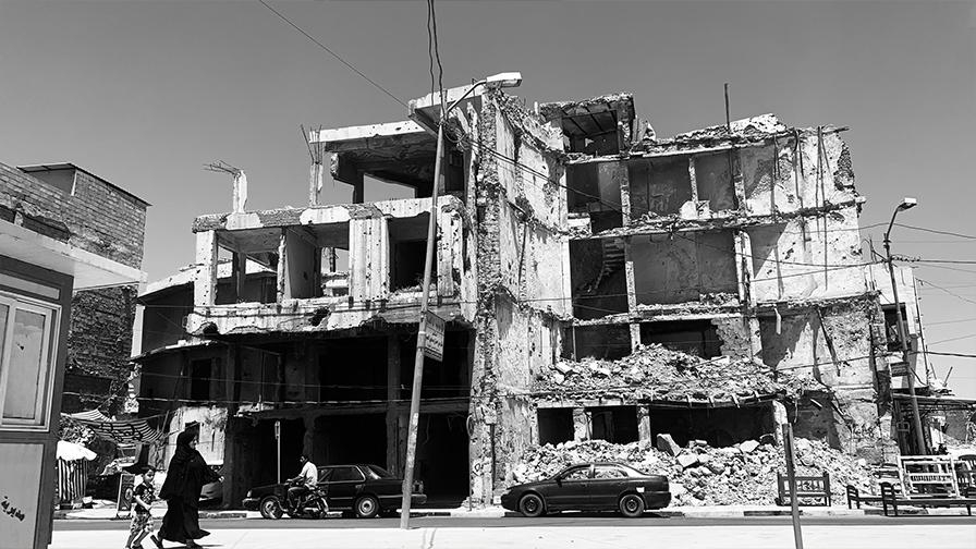 Black and white photo of an apartment building blown apart in the aftermath of a bombing.