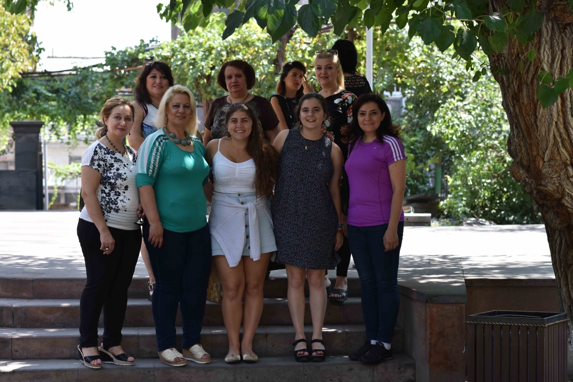 Ani and Anoush pose with a group of Armenian women on stone steps underneath a tree
