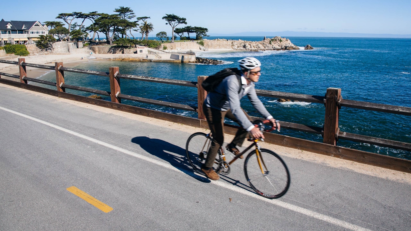 Student rides bike along the coast line of Monterey, CA