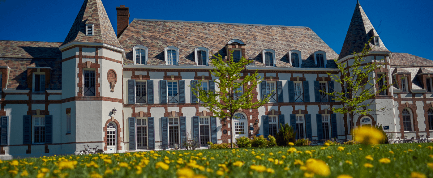 Photo of Le Chateau in springtime with green grass and daffodils.