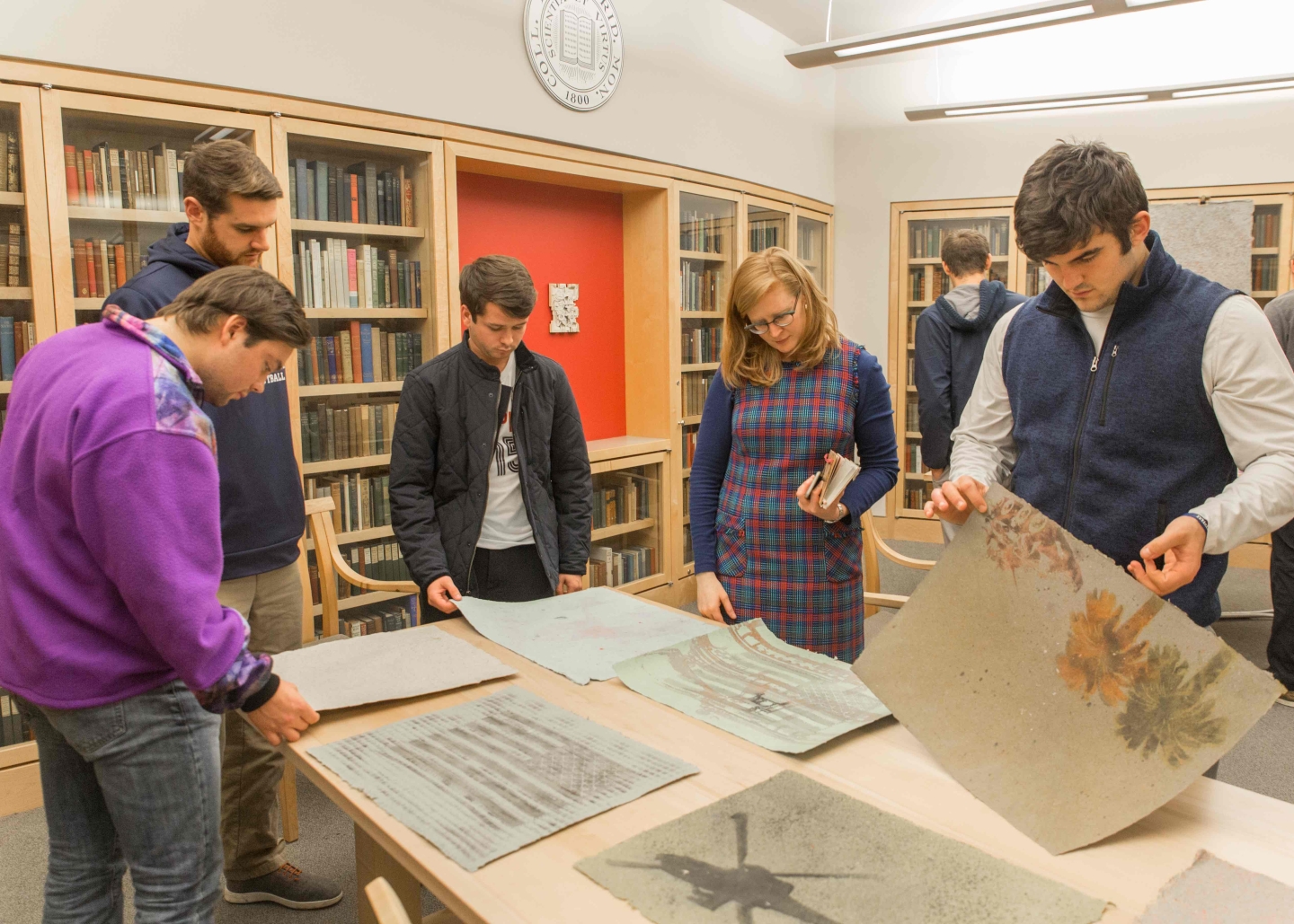 Students engage and lift up the pieces of art from the table.