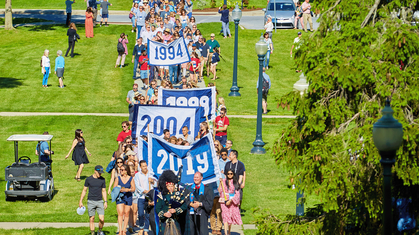 Convocation parade at Reunion, with banners from classes between 2019-1994 visible