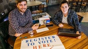 Two Middlebury students sit at a table encouraging students to vote.