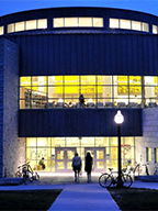 Two figures silhouetted in the warm lights of the Davis Family Library at dusk