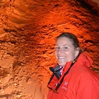 AJ Vasiliou in a cave lit with an orange light