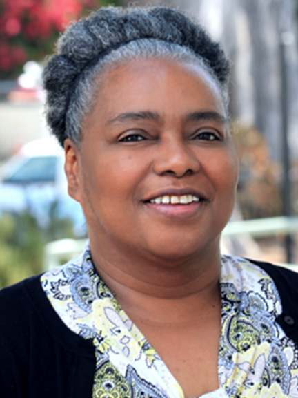 Portrait of Dollie Pope wearing a floral blouse and black blazer.