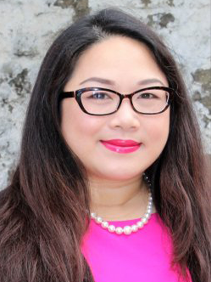 Portrait of Betty Chau Nguyen  wearing a pink blouse, pearl necklace, and glasses.