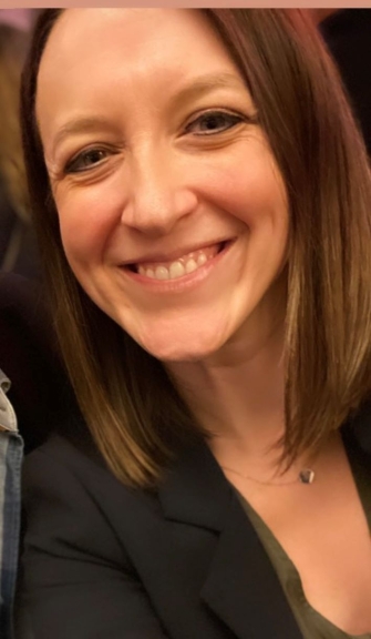 A Smiling woman with Shoulder length hair and a black blazer