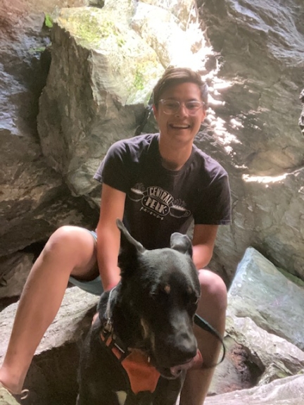Smiling person with dog sitting in a rocky outcropping