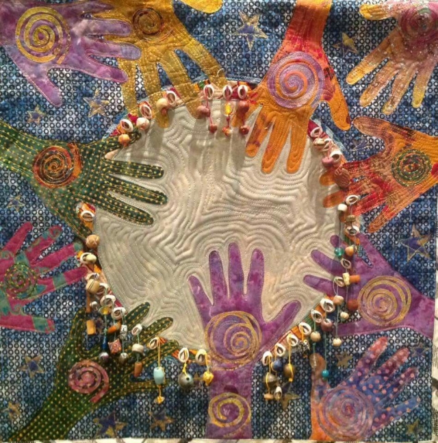 quilt showing multicolored hands on drum head