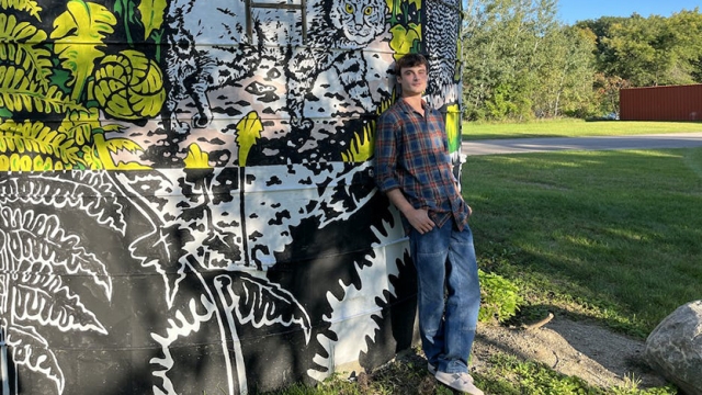 Wyatt Robinson ’24.5 leaning against the silo he painted.