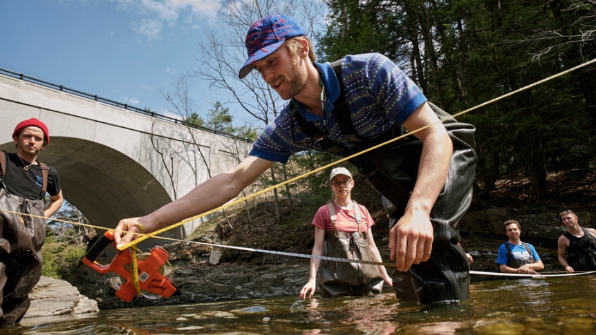 Students in waders work with samples in a local Middlebury river.