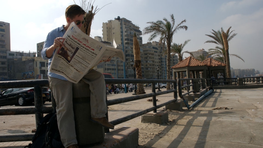 A man reads a newspaper in a Latin American city.