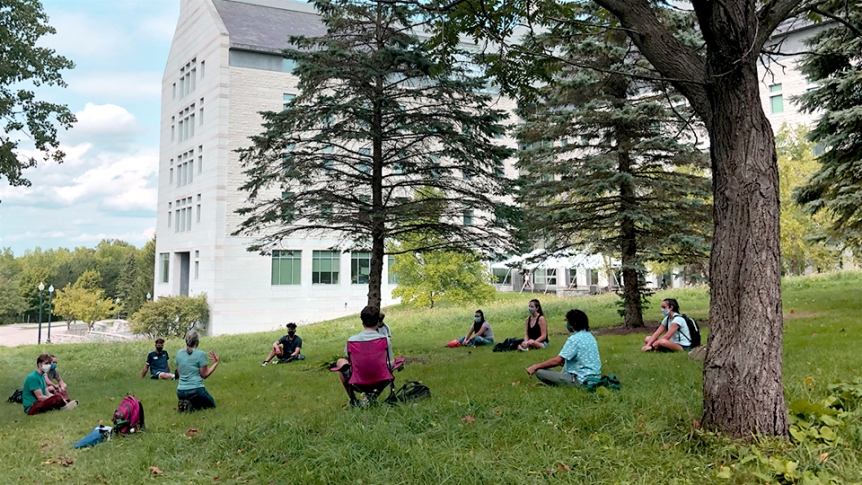 Middlebury students sit in an outdoor setting attending class.