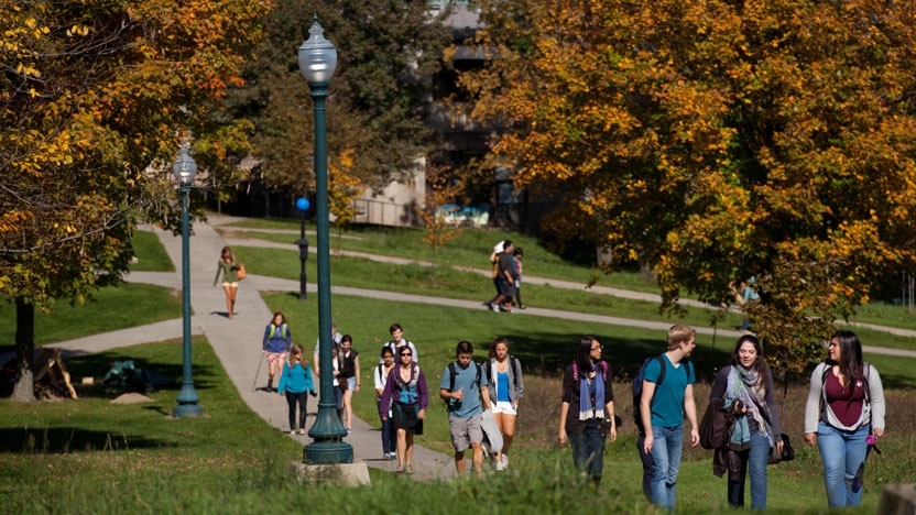 Students walk through campus between classes on a sunny fall afternoon.