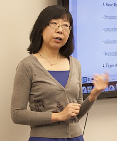 Hang Du presenting in front of a slide show on a large monitor