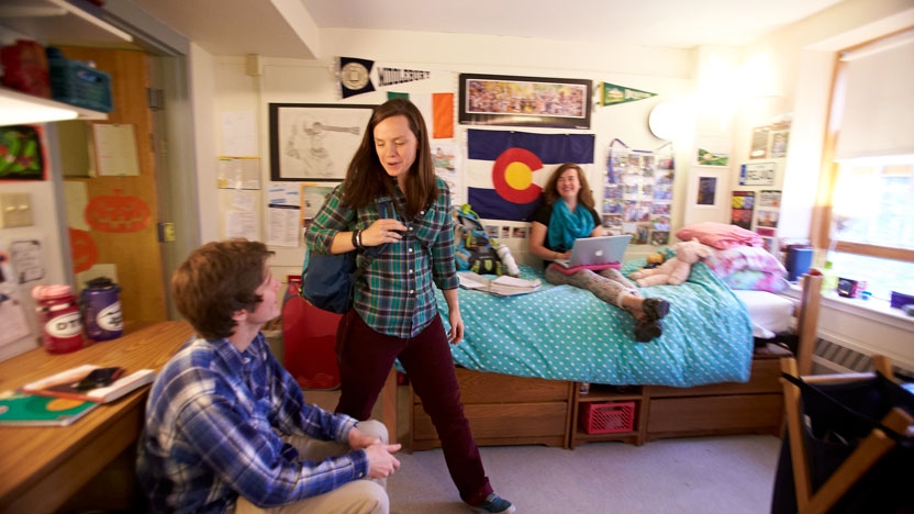 Interior view of a residence hall room with students hanging out.