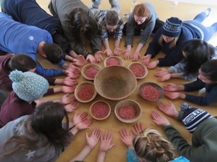 prajna members gathered around with hands open around cups of beans