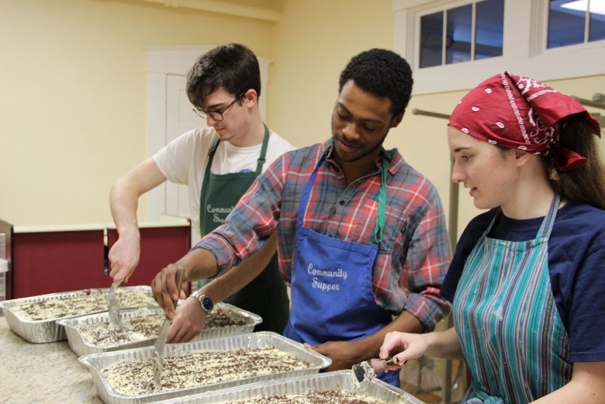 three students frosting cakes for Community Supper