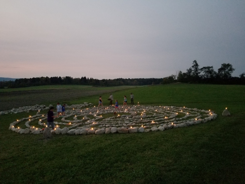 labyrinth stones with candles lighting the way at night with the sun setting