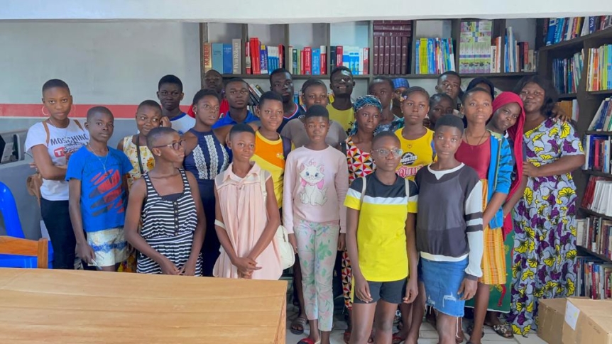 A class of young students poses for a group photo amidst their new library space.