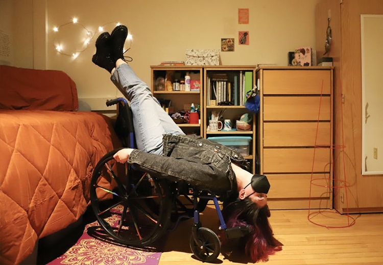 Photo of Middlebury Student Isabel Linhares seated upside-down in their wheelchair